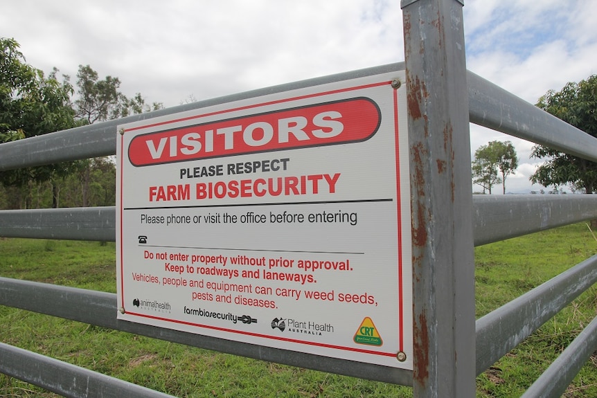 A close up of a white biosecurity sign with red and black writing.