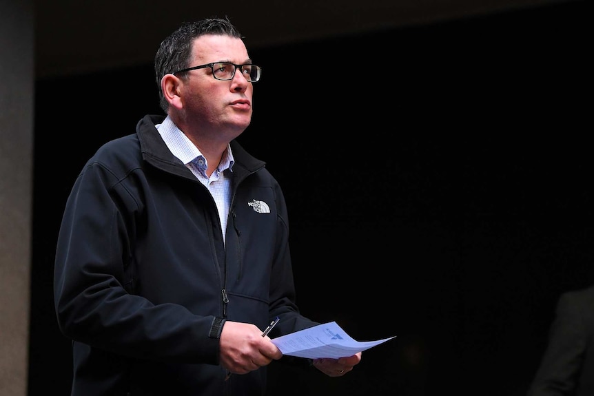 Daniel Andrews holds his talking points as he arrives at the press conference