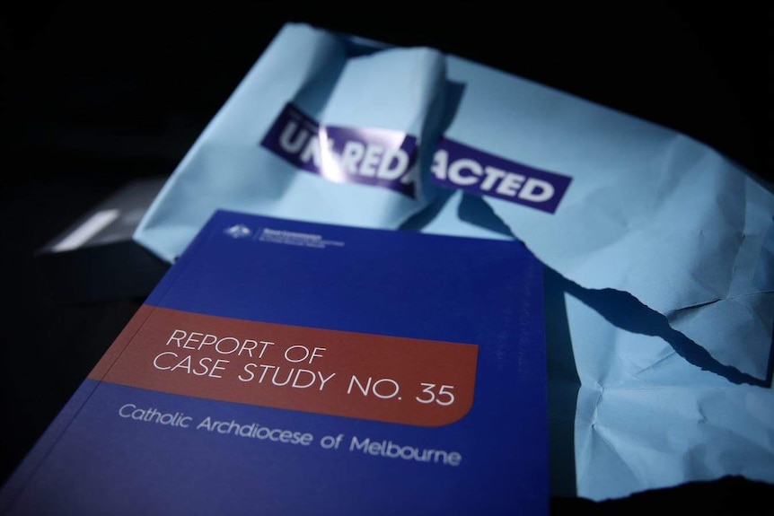 A blue copy of the royal commission's report into the Catholic Archdiocese of Melbourne sits in front of a torn envelope.
