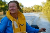 A woman with a blue shirt and a yellow lifejacket in a dingy along the Darling River near Menindee