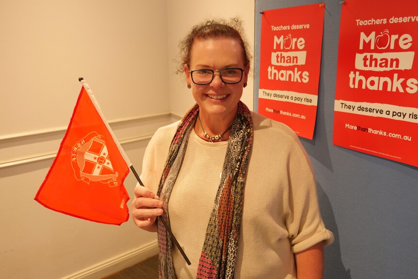 A woman wearing a scarf holds a small flag.