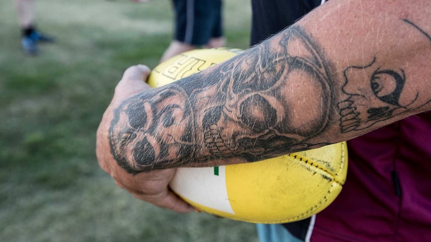 Tattooed arm holding Australian Rules football at team training, Tasmania.