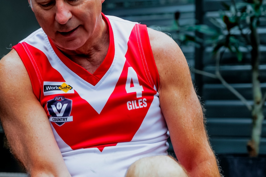 A close-up of a man wearing a footy jumper.