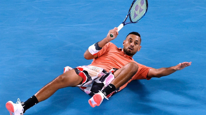 Nick Kyrgios slides on the court while playing a shot