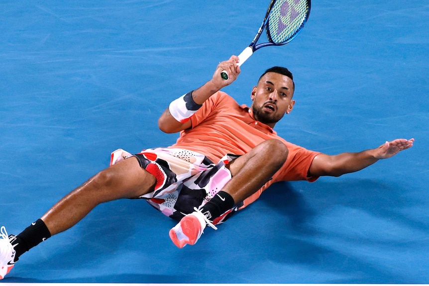 Nick Kyrgios slides on the court while playing a shot