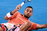 Nick Kyrgios slides on the court while playing a shot