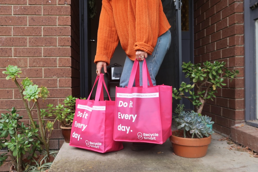 A woman puts two RecycleSmart shopping bags on her doorstep