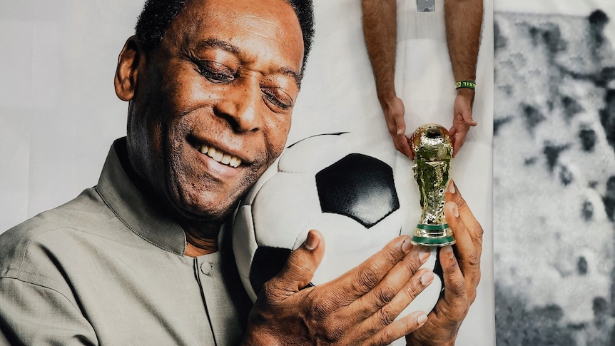 Pele holding a soccer ball close to his face with his eyes closed
