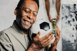Pele holding a soccer ball close to his face with his eyes closed