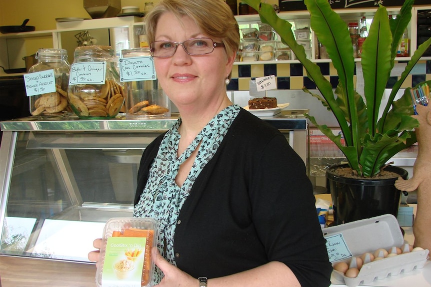 A woman stands in a delis shop space.