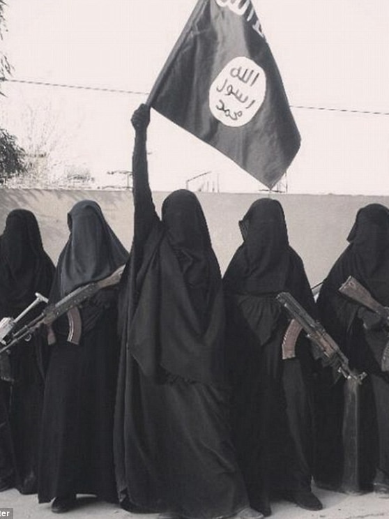 Five women wearing burquas - four hold machine guns, the middle woman holds an ISIS flag aloft.