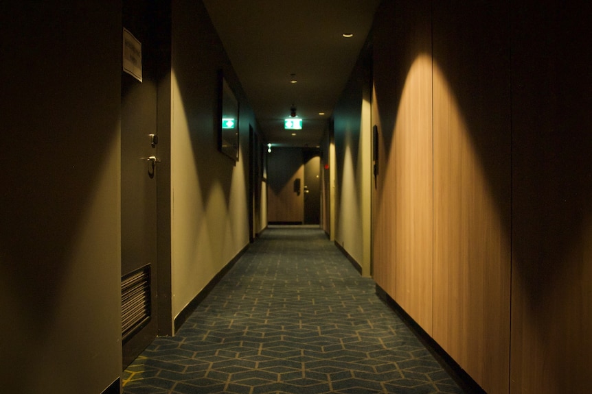 A long shot of an empty hotel corridor, with doors running along either side.