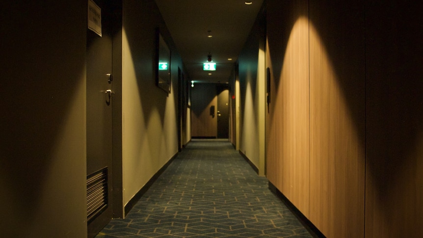 A long shot of an empty hotel corridor, with doors running along either side.