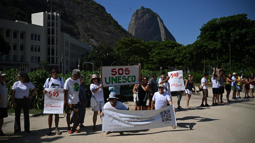 people holding signs in protest against zip-line attraction.