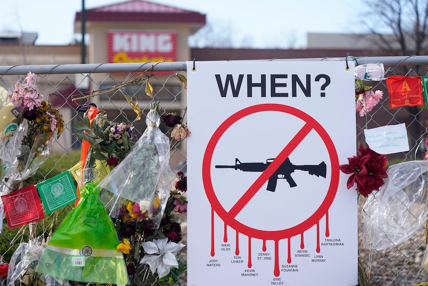 Tributes hang on the temporary fence surrounding the parking lot in front of the scene of a shooting.