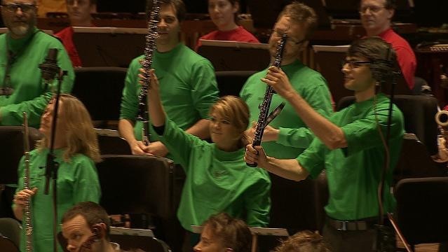 Musicians hold up wind instruments in orchestra pit
