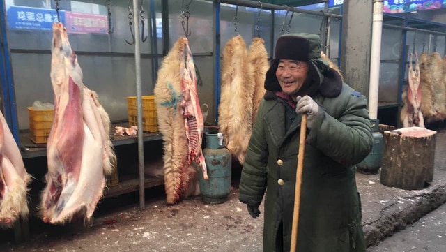 A man stands next to his stall at a meat market in Zhidan, Shaanxi province, China