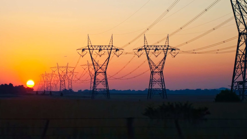 Power lines on a plain with the sun setting behind them