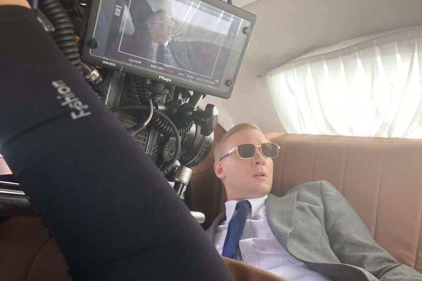 Tom in a car being filmed