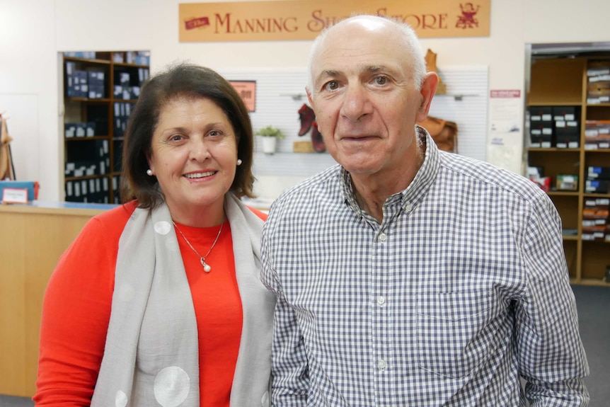 A man and woman smile at the camera as they stand in a store.