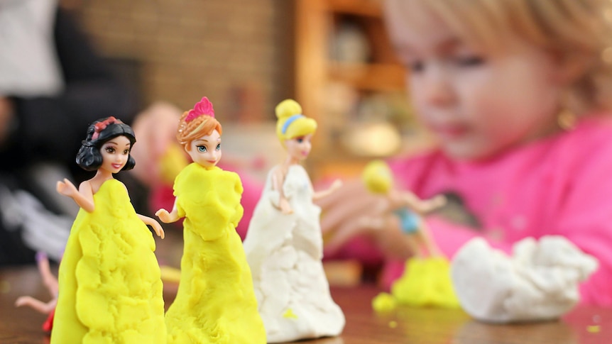 small clay models of women wearing yellow and white princess dresses, girl in background making another figure