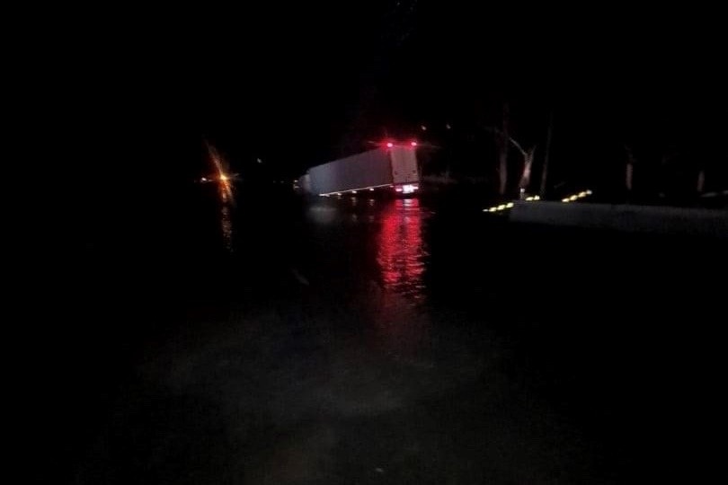 A truck is pictured in darkness with its front in floodwater