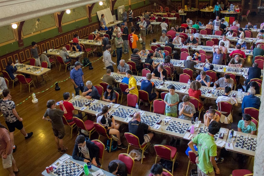 A room lined with tables filled with people playing chess