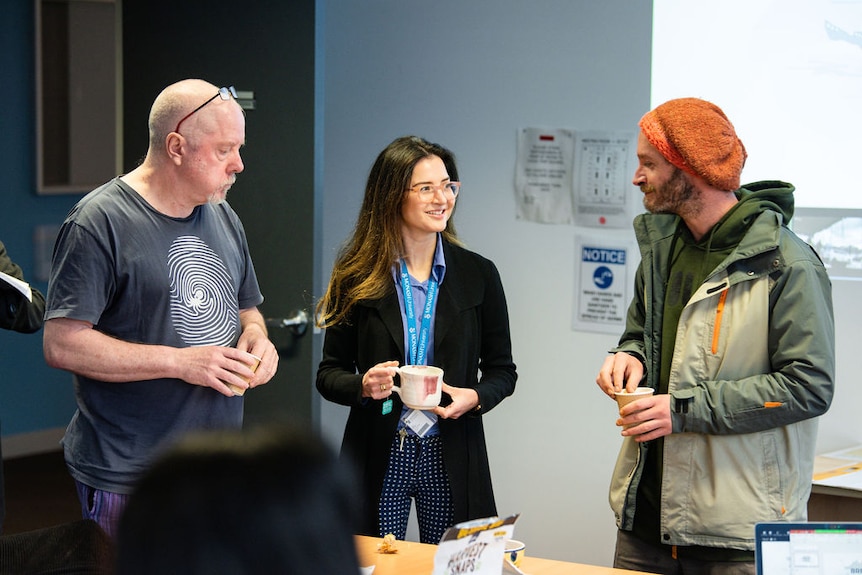 Two men and a woman speaking in a room