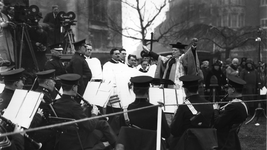 a black and white image of Ethel Smyth with her arms raised conducting a band