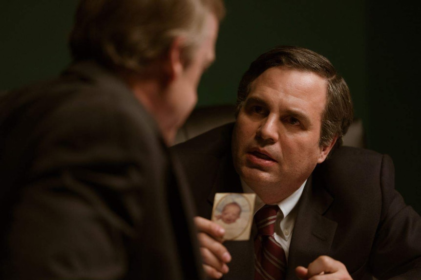 The actor Mark Ruffalo as a lawyer brandishing a baby photo to a man in a suit in the movie Dark Waters