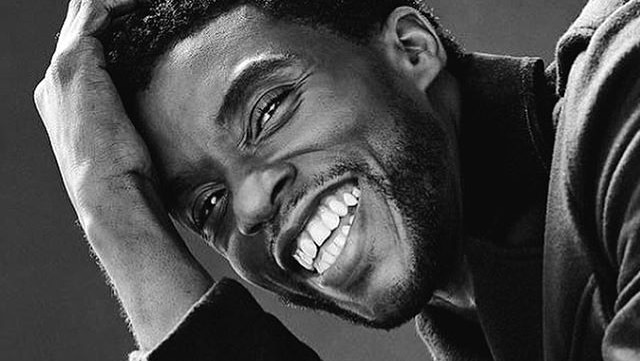 A black and white photograph of Chadwick Boseman smiling.