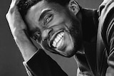 A black and white photograph of Chadwick Boseman smiling.