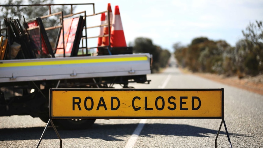 A road closed sing and a ute carrying witches' hats and signs.