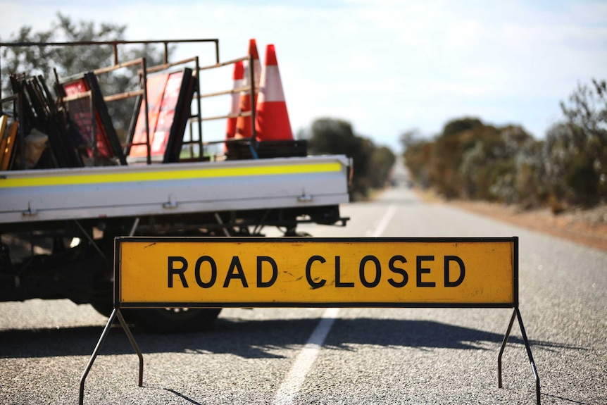 A road closed sing and a ute carrying witches' hats and signs.