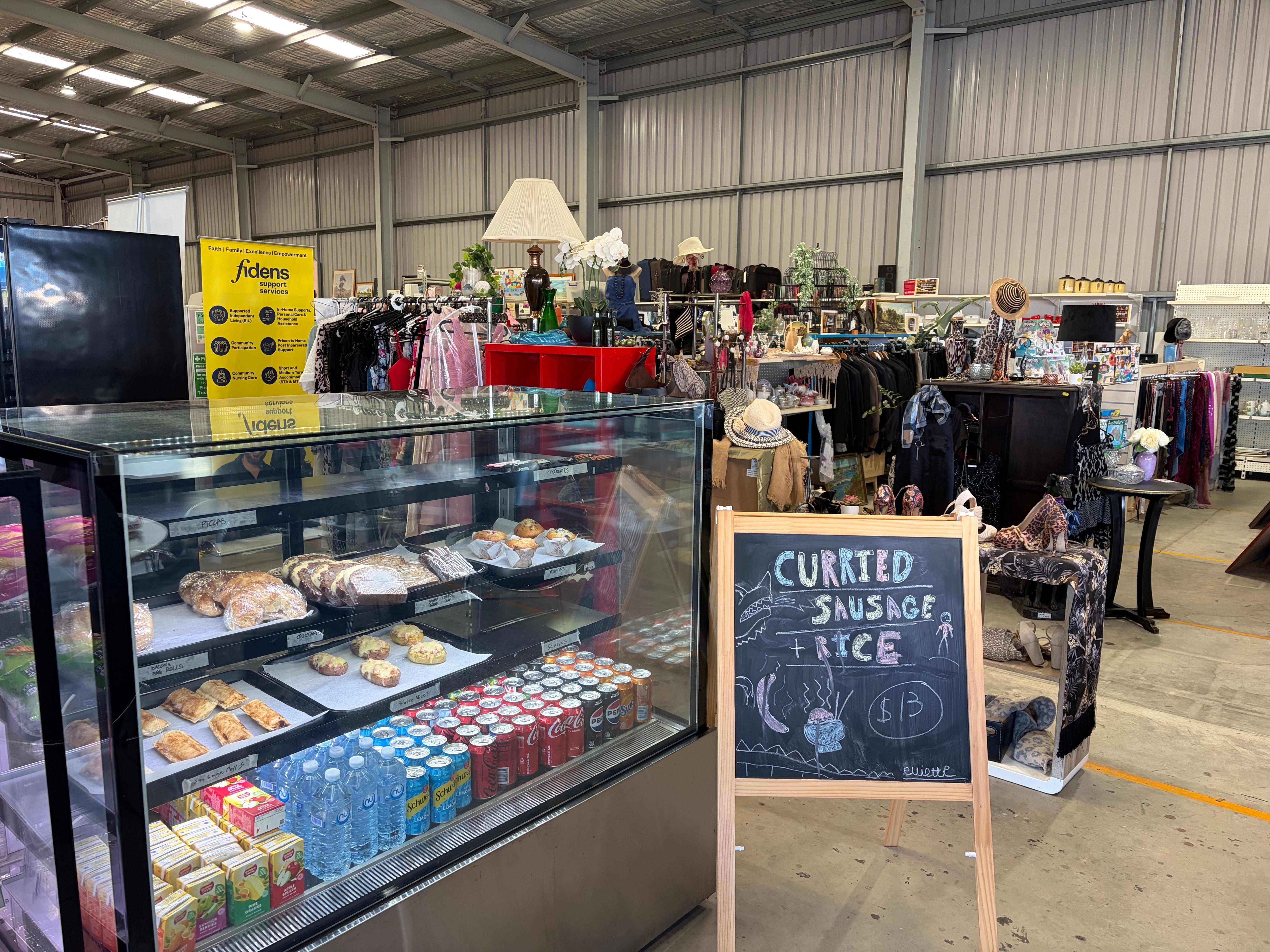 A cafe concierge within a warehouse surrounded by clothing and item racks