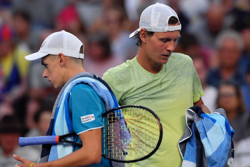 Tomas Berdych (R) and Alex De Minaur pass each other the change of ends at the Australian Open.