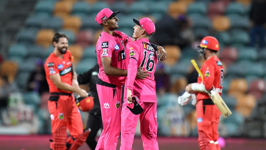 Sydney Sixers' Gurinder Sandhu and Daniel Hughes hug in the field during a BBL game against the Melbourne Renegades.