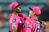 Sydney Sixers' Gurinder Sandhu and Daniel Hughes hug in the field during a BBL game against the Melbourne Renegades.