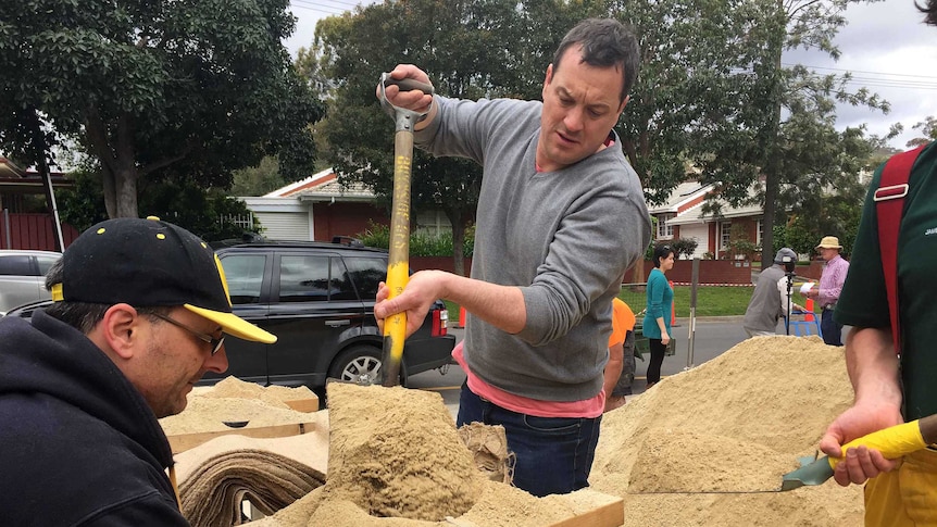 Men fill sandbags with the SES at Burnside.