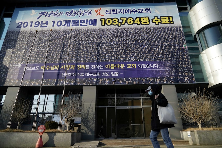 A Korean building with a man in a face mask walking by