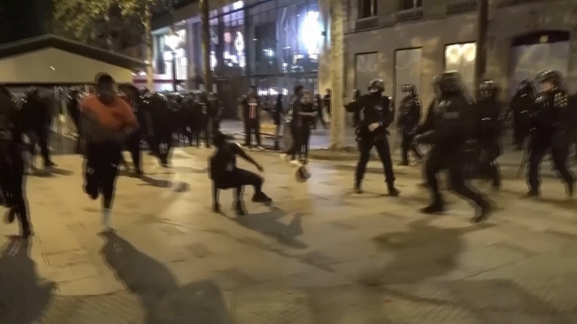 Police in riot gear chase a group of runners on a Parisian street