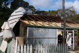 A tin roof hangs off the side of a house after being ripped off by strong winds.