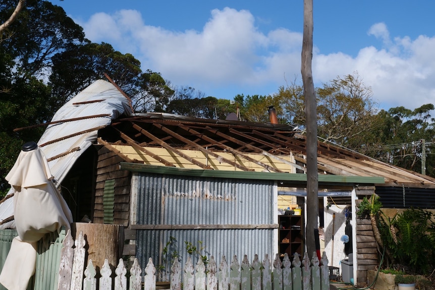 A tin roof hangs off the side of a house after being ripped off by strong winds.