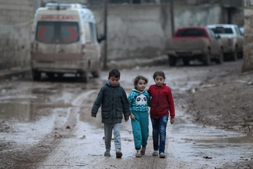 Children walk near a parked ambulance in al-Rai town, northern Aleppo province, Syria, December 27, 2016.