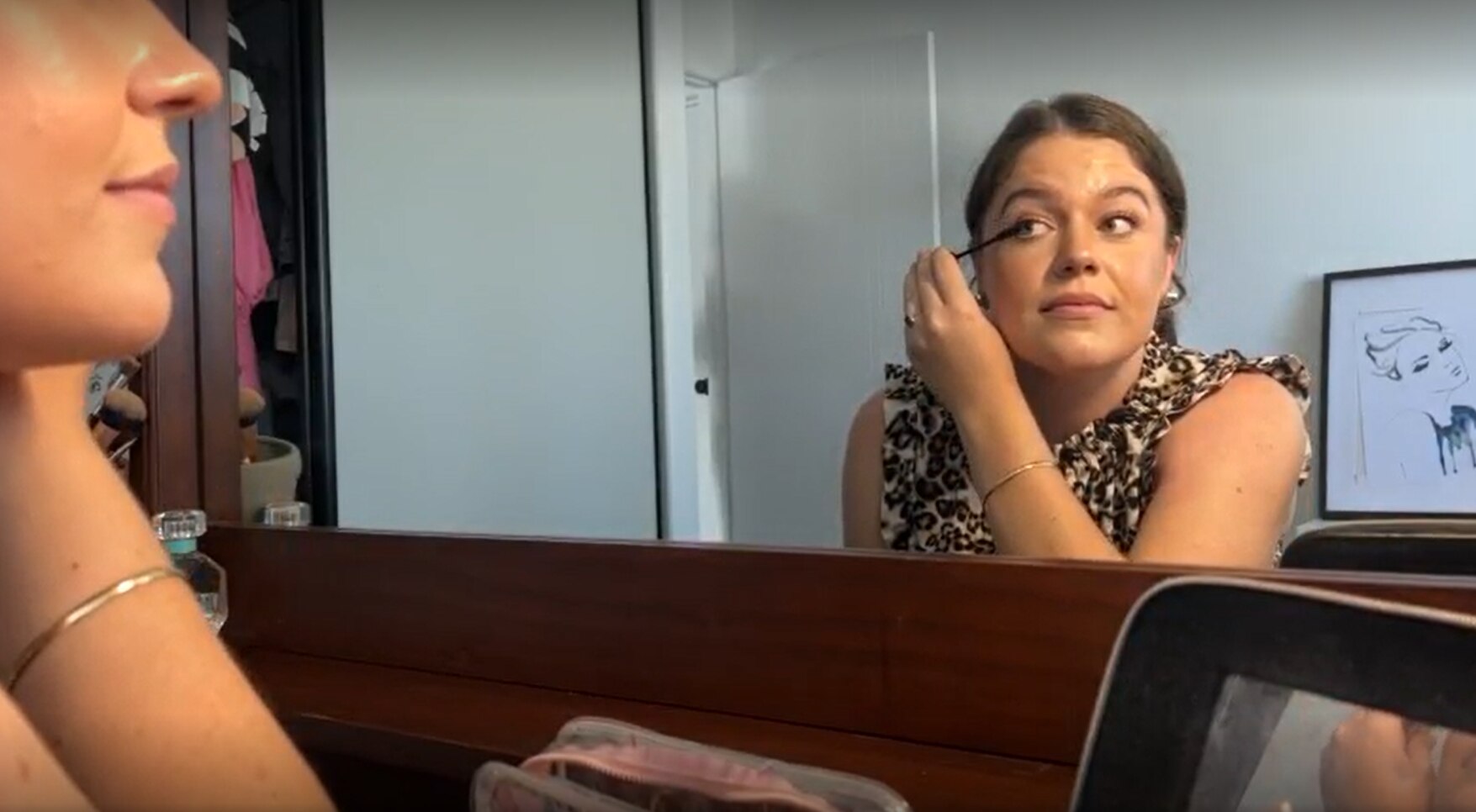 Girl puts mascara on at a mirror.
