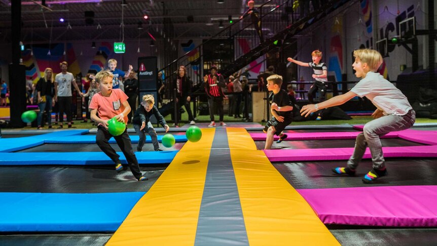 a group of boys playing a ball game at bounce trampoline centres