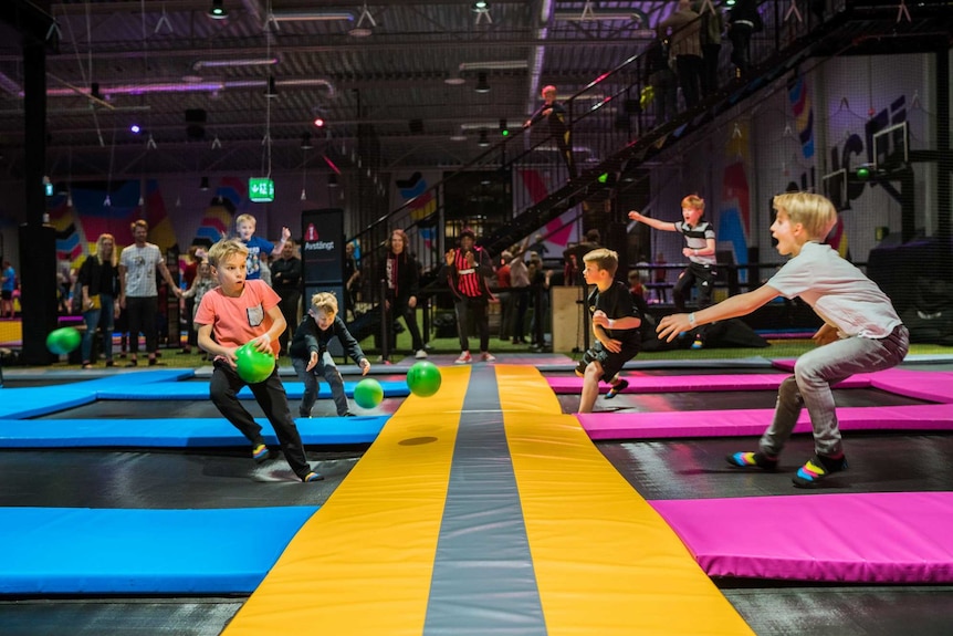 a group of boys playing a ball game at bounce trampoline centres