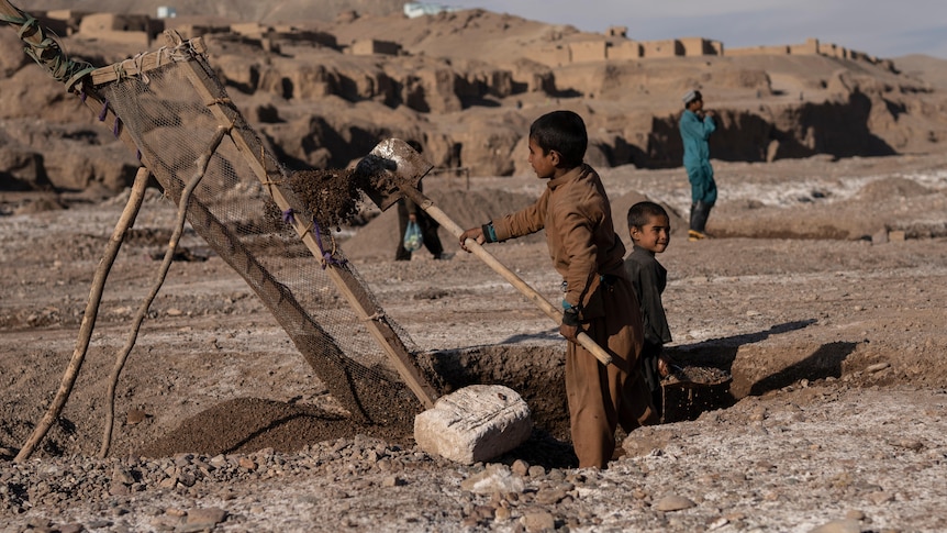 two boys dig sand from the riverbed in Kamar Kalagh village near Herat in the day time