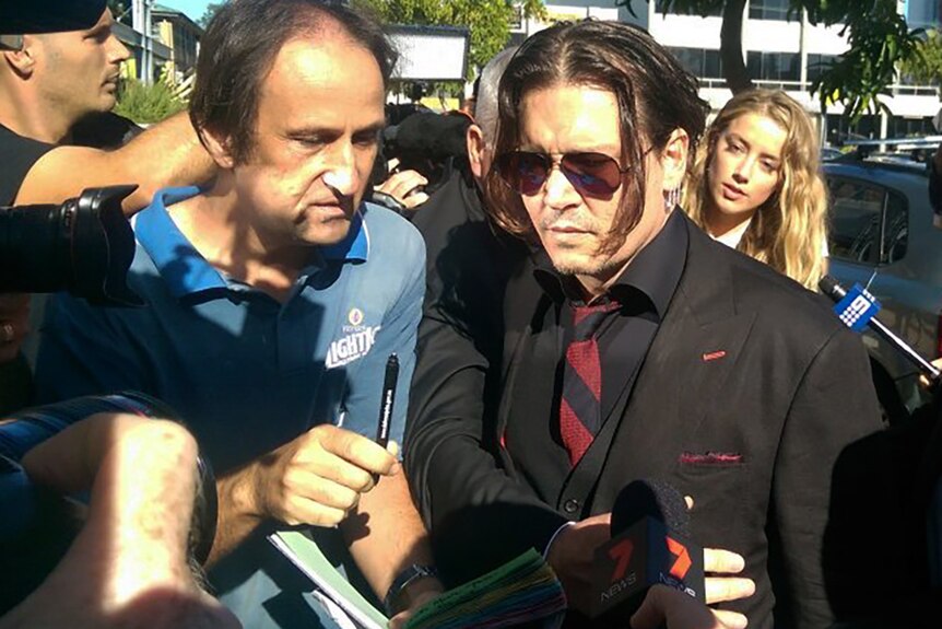 An autograph hunter amid the media pack confronts actor Johnny Depp, his wife Amber Heard is behind him