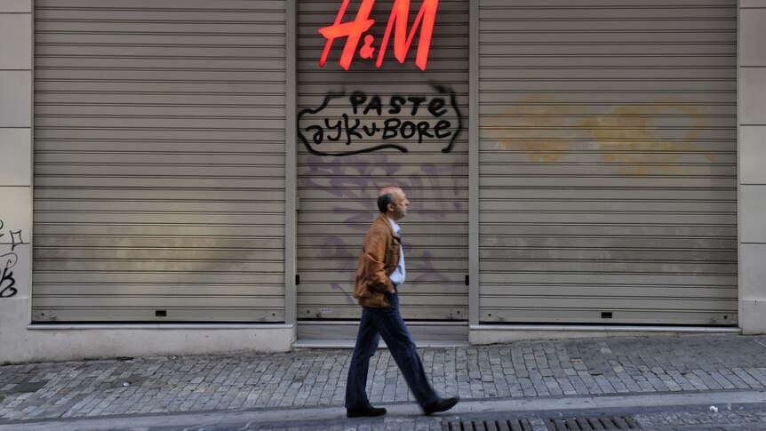 Man passes by closed shop in Athens